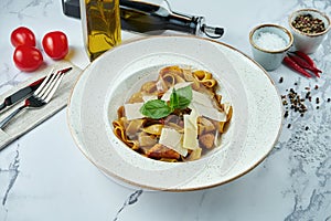 Appetizing Italian pasta with salmon, sun-dried tomatoes and parmesan in a white plate on a marble background. Fettuccine with