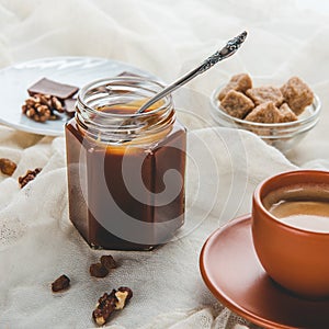 Appetizing jar of caramel jam and cup of coffee