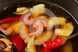 Appetizing looking seafood soup with mussels shrimp red pepper in a plate on a wooden table. fresh seafood. tasty dish