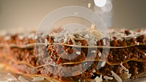Appetizing meat lasagna is sprinkled with pieces of grated cheese. Parmesan.Very beautiful studio shot. Camera Phanto