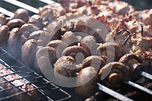 Appetizing mushrooms close-up on the grill on the background of roasting kebab