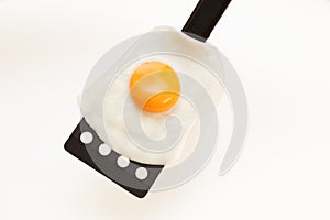 Appetizing and Perfectly Fried Egg on a Spatula, isolated on white background