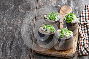 Appetizing pickled herring rolls stuffed with cream cheese and egg mass served on wooden board