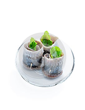 Appetizing pickled herring rolls stuffed with cream cheese and salad leaves isolated on white