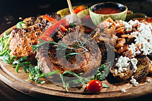 Appetizing plate with beef steaks with potatoes, hot chili peppers, beans and young potatoes, onions, cheese, pickled cucumners