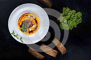 An appetizing pumpkin soup is served in a white plate in a restaurant