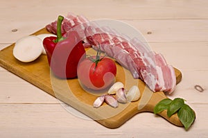 Appetizing raw pork pieces of bacon and vegetables