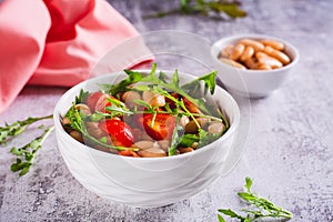 Appetizing salad of canned white beans, cherry tomatoes and arugula in a bowl