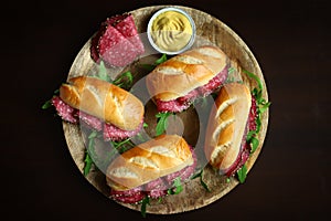 Appetizing salami sandwiches with arugula and mustard on a wooden board
