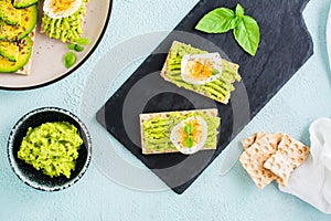 Appetizing sandwiches of crispy bread with avocado and boiled egg on slate. Top view