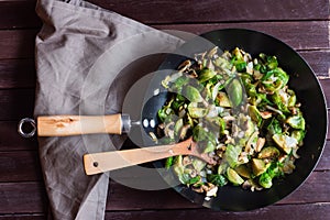 Appetizing sauteed brussels sprouts and champignons in skillet with wood turner
