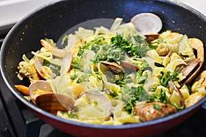 Appetizing seafood pasta with vongole and fried shrimps in a pan photo