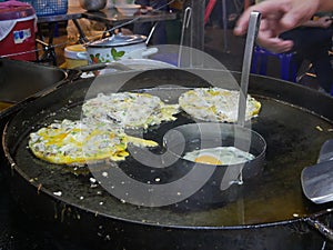 Appetizing sizzling oyster omelette  Hoy Tod  being cooked on a hot pan at night, Chiang Mai, Thailand - Thai delicious street