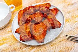 Appetizing smoked chicken wings dished up in a plate on laid restaurant table