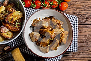 Appetizing stew of pork tenderloin meat cooked in the wok, cut into cubes. With roasted and golden potatoes, garlic, salt, oregano