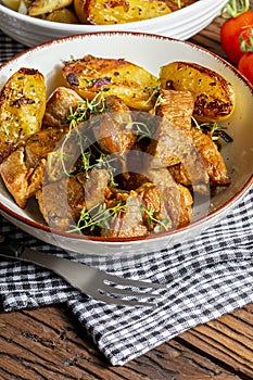 Appetizing stew of pork tenderloin meat cooked in the wok, cut into cubes. With roasted and golden potatoes, garlic, salt, oregano