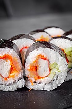 Appetizing sushi roll futomaki with cucumber crab stick and masago on a black stone plate