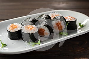 appetizing sushi roll futomaki with salmon on a white plate. Sushi menu.