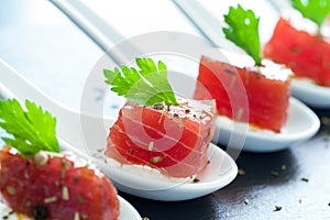 Appetizing tuna morsel on ceramic spoons.
