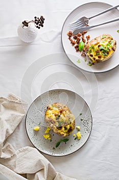 Appetizing twice-baked potatoes in their skins with cheese and bacon crumbs on plates on a wooden table. Flexitarian Diet. Top and