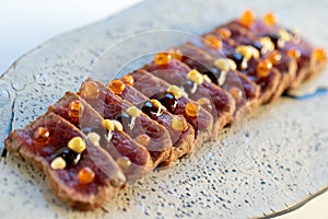 Appetizing wagyu beef tataki on wooden plate.