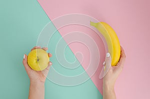 Apple or banana Creative trendy concept on bright split color background. woman hand holding yellow small apple and