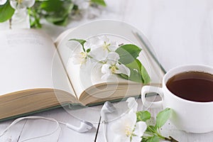 Apple blossom on book, cup of tea