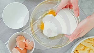 Apple cake recipe. Mixing eggs and sugar in a glass bowl, close-up view, flat lay