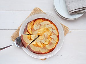 Apple cake on white plate with one slice on a cake server