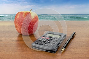 Apple calculator pencil lie on the table against the backdrop of the sea