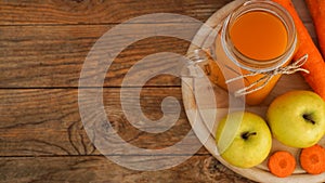 Apple and carrot juice in glass, fresh vegetables and fruits on wooden