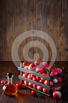 Apple cider vinegar in a glass bottle. Apples in an old wooden box.