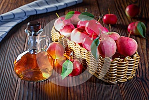 Apple cider vinegar in a glass bottle. Apples in an old wooden box.