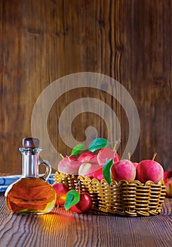 Apple cider vinegar in a glass bottle. Apples in an old wooden box.