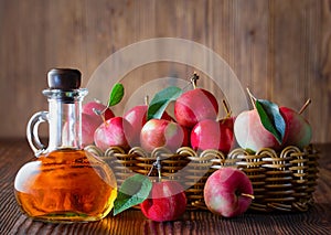 Apple cider vinegar in a glass bottle. Apples in a wicker basket.