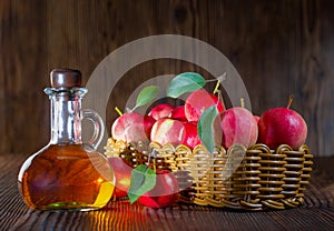 Apple cider vinegar in a glass bottle. Apples in a wicker basket.