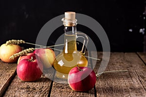 Apple Cider Vinegar in Glass Bottle and Red Fresh Apples Wooden Background