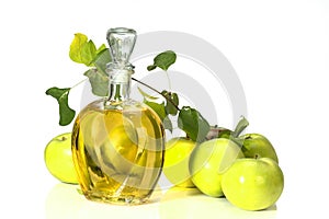 Apple cider vinegar in a glass vessel and green apples
