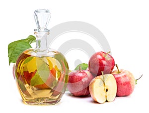 Apple cider vinegar in a glass vessel and red apples