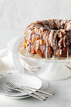 An apple cinnamon pull apart bread on a pedestal stand with dishes for serving.