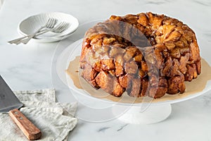 An apple cinnamon pull apart bread on a pedestal stand with dishes for serving.