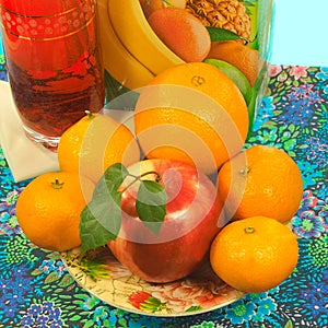 Apple and citrus fruit on a plate, glassful and carton of juice