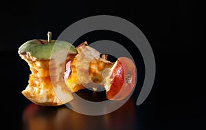 An apple core on a black background with reflexion. Ecology concept