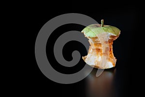 An apple core on a black background with reflexion. Ecology concept