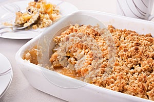 Apple crumble in a baking dish and a portion on a plate