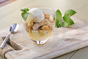 Apple crumble topping vanilla ice cream served with melisa in glass and wooden tray on table. photo