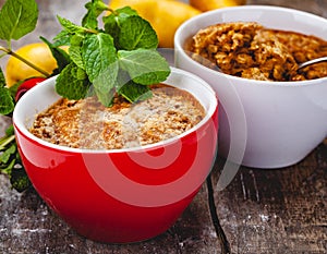 Apple crumble in two cups on wooden rustic background.
