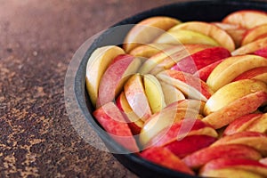 The apple cut by pieces in a black pig-iron frying pan on a rusty metal surface. Preparation for apple pie.