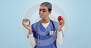 Apple, donut and doctor in studio with choice for healthy eating, diet and detox on blue background. Thinking