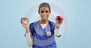 Apple, donut and portrait of nurse with choice for healthy eating, diet and detox on blue background. Happy, healthcare